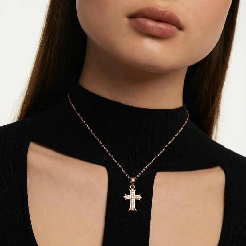 Gold-plated cross pendant necklace with pavé stones worn at the neck.