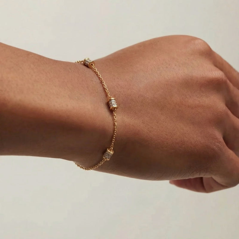 Gold-plated minimalist chain bracelet with pavé-studded barrel stations worn on the wrist.