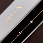 Close-up of the gold-plated chain featuring a clear stone cross and an evil eye charm