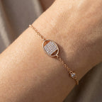 Rose gold bracelet with a diamond accent on a wrist against a neutral background