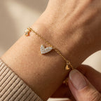 Gold-plated heart charm bracelet worn on wrist