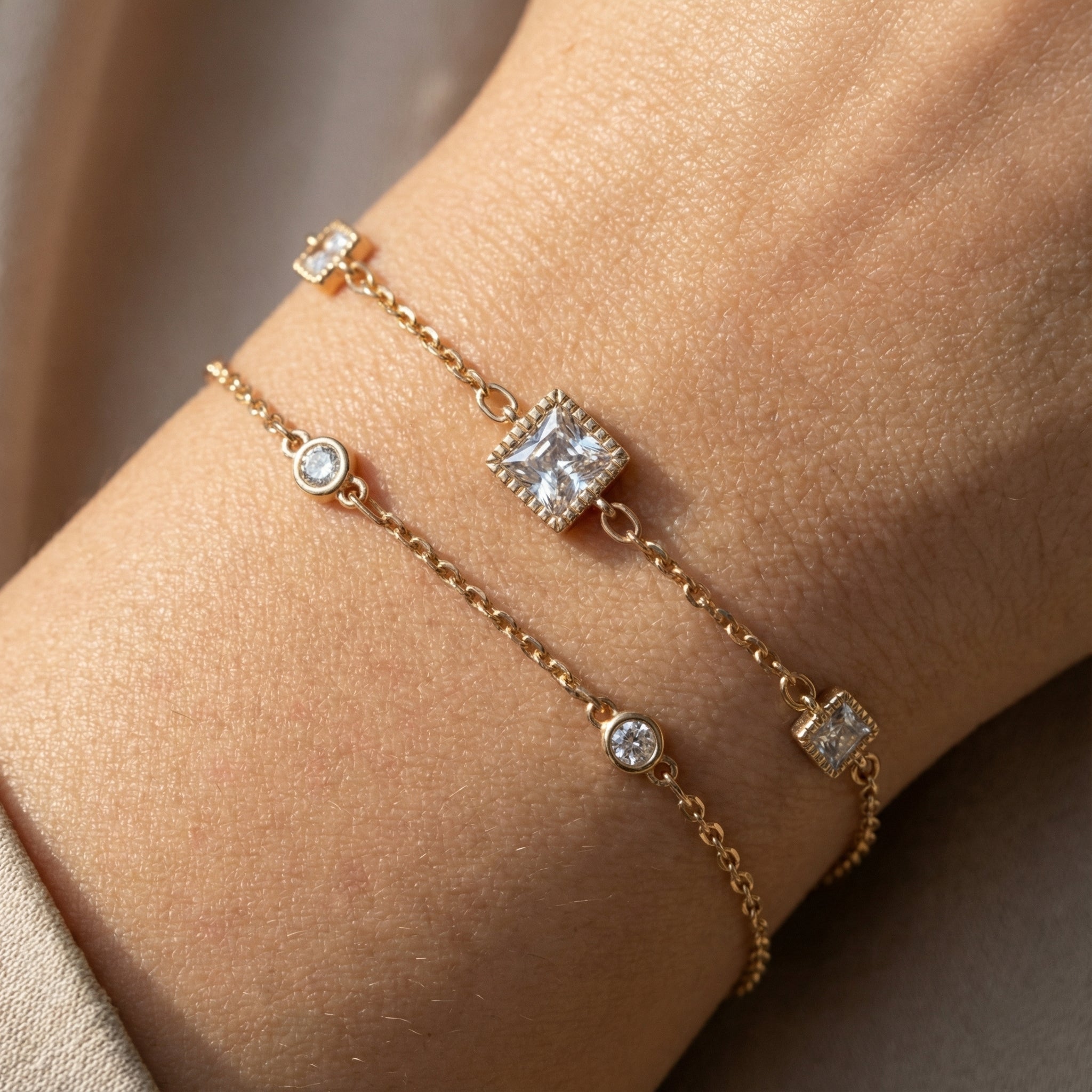 Layered gold-plated square charm bracelet worn on wrist
