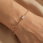 Gold-plated rectangular charm bracelet worn on wrist