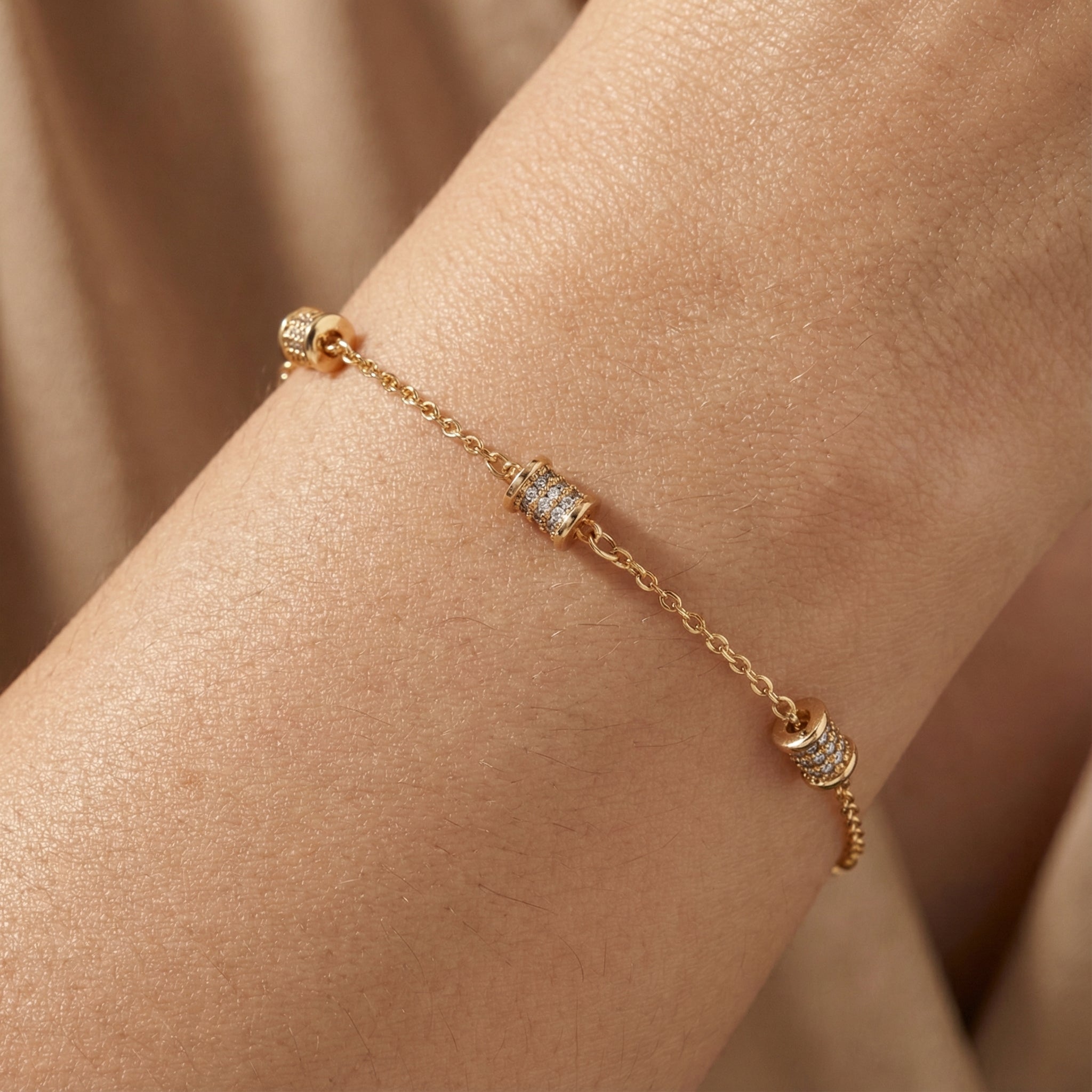 Gold-plated barrel charm bracelet worn on wrist