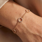 Gold-plated circle bracelet worn on wrist with minimal open ring charms