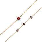 Close-up of red evil eye charm on double-layer gold chain bracelet with black bead accents on a white background