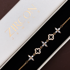 Gold bracelet with clover and floral designs on a Zircon branded box