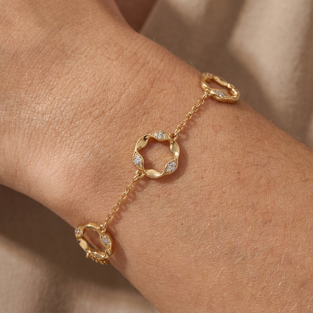 Gold bracelet with diamond accents on a wrist against a neutral background