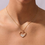 Gold necklace with a heart-shaped pendant on a person's neck against a neutral background