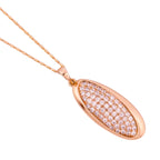 Elongated oval pavé pendant necklace photographed at an angle showing stone sparkle and gold rim