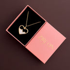 Heart-shaped gold necklace with zirconia stones in a pink Zircon box on a dark background