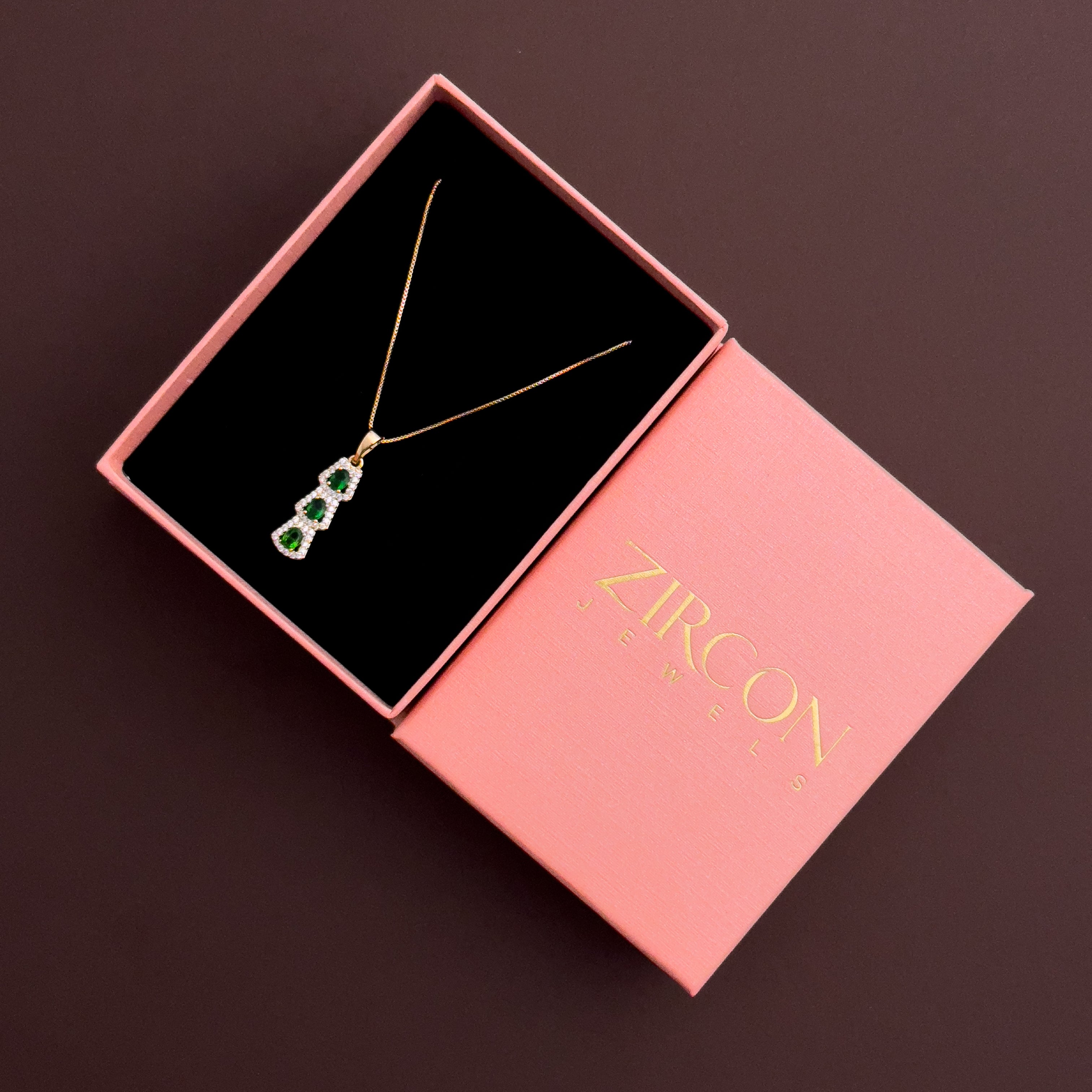 Jewelry box with a necklace featuring green gemstones on a dark background